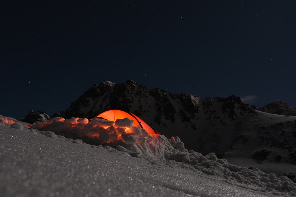 Illuminated tent at basecamp under a starry mountain night