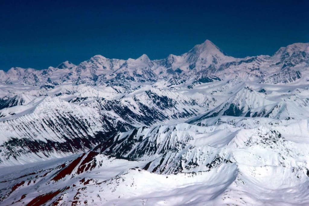 Aerial view of snow-covered mountain range under a deep blue sky